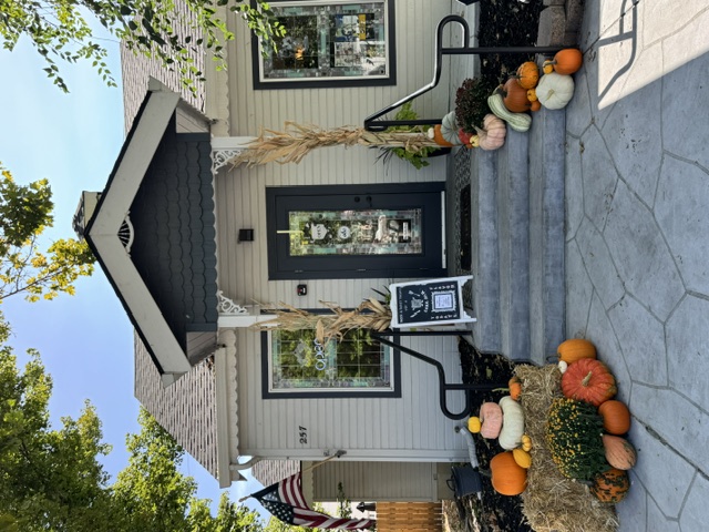 Porch glowing at night with string lights and a pumpkin ladder